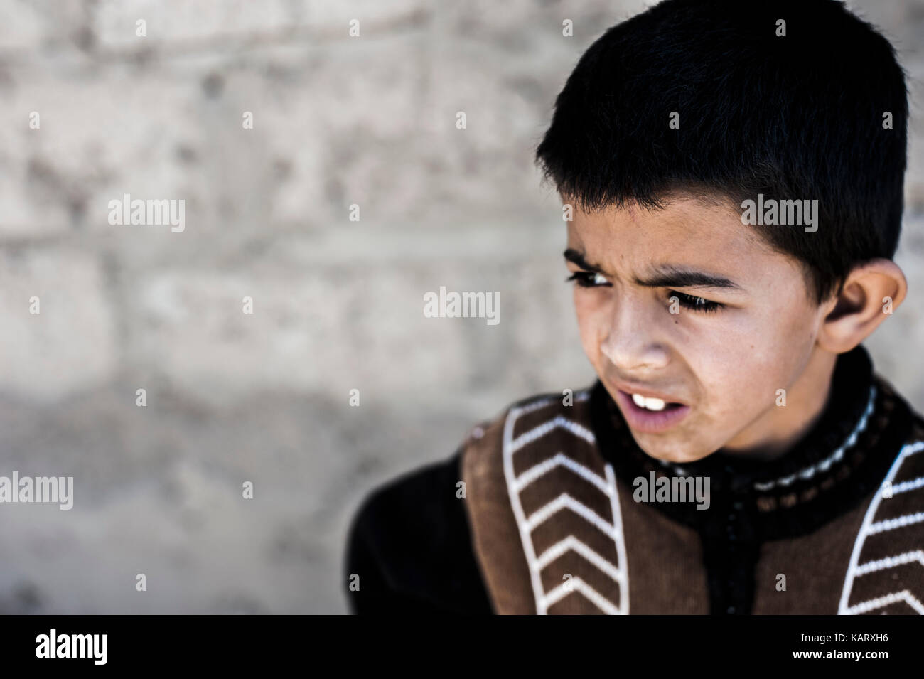 Portrait d'un garçon à la recherche jusqu'à l'appareil photo dans le village de Merzouga, Maroc Banque D'Images