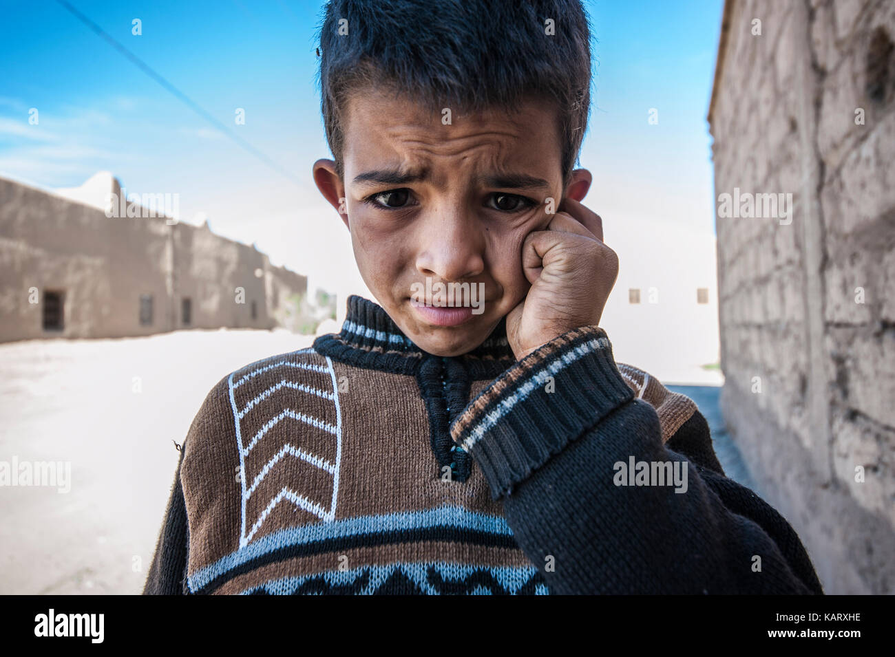 Portrait d'un garçon à la recherche jusqu'à l'appareil photo dans le village de Merzouga, Maroc Banque D'Images