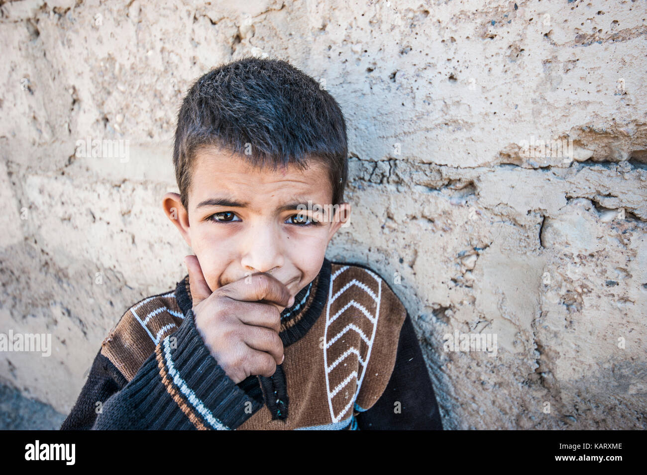 Portrait d'un garçon à la recherche jusqu'à l'appareil photo dans le village de Merzouga, Maroc Banque D'Images