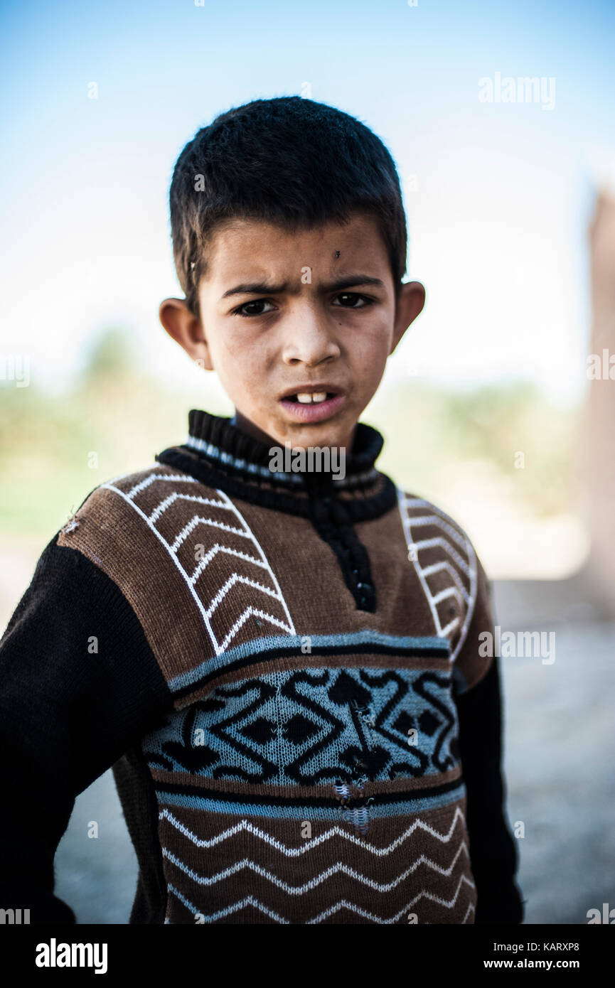 Portrait d'un garçon à la recherche jusqu'à l'appareil photo dans le village de Merzouga, Maroc Banque D'Images