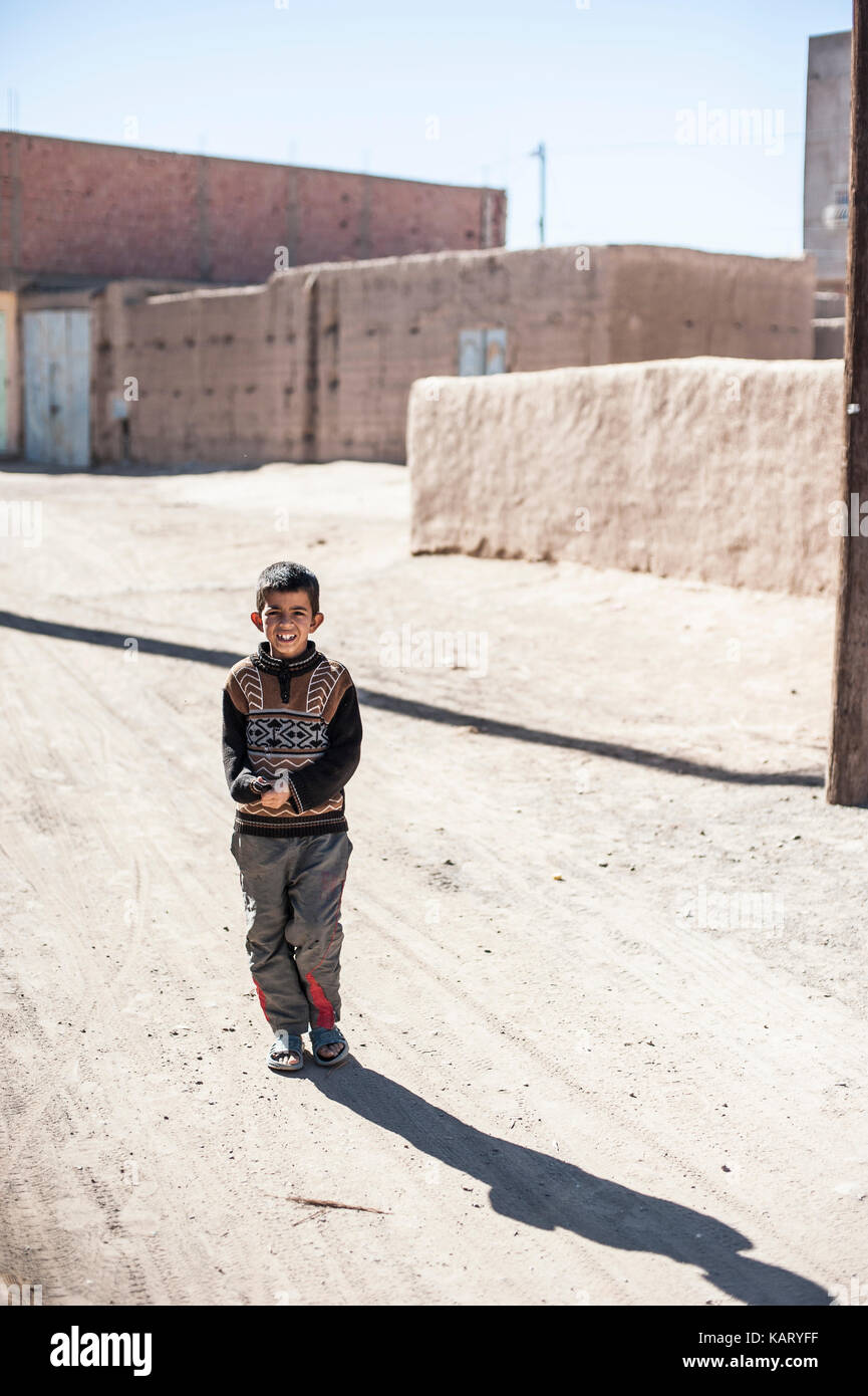 Portrait d'un garçon à la recherche jusqu'à l'appareil photo dans le village de Merzouga, Maroc Banque D'Images