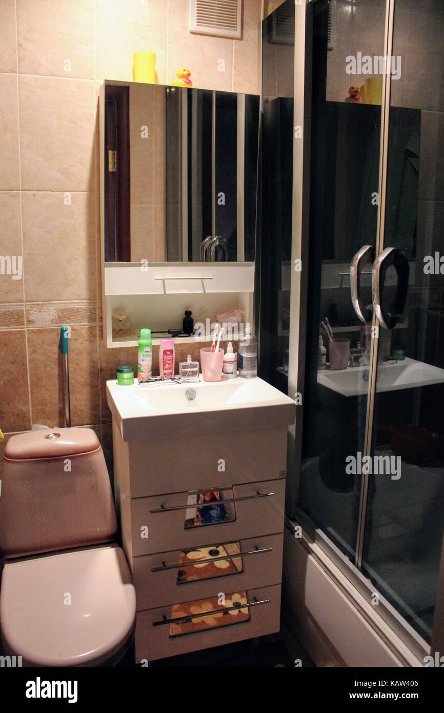 La salle de bains avec douche dans un petit appartement est faite dans des tons doux, compact et fonctionnel. Banque D'Images