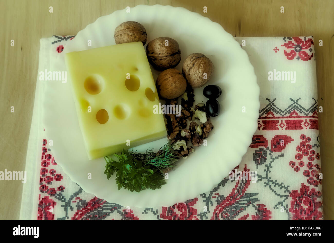 Sur la table sur une plaque blanche pour obtenir le fromage, les noix et les olives. L'effet de la Polaroid. Banque D'Images