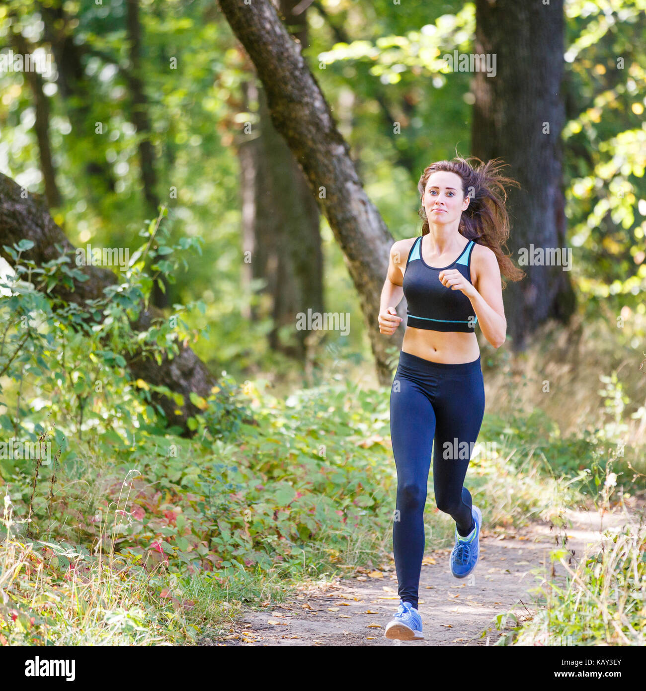 Young smiling sporty woman running in park le matin. fitness petite fille jogging en parc. trail running concept background Banque D'Images