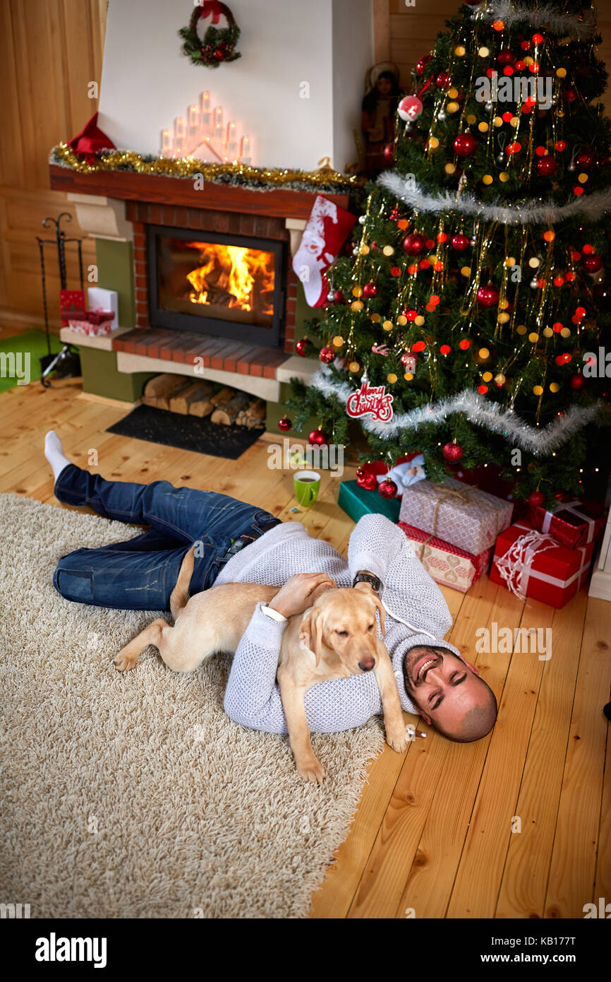 Profitez de l'homme au chien la veille de Noël près de cheminée Banque D'Images