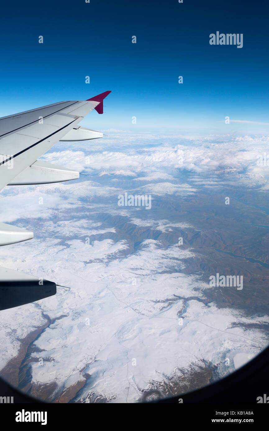 Vue depuis l'avion fenêtre pour les montagnes enneigées Banque D'Images