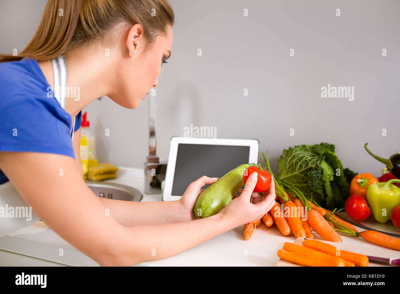 Femme dans la cuisine à la recherche d'une recette sur internet, la technologie moderne et la cuisine Banque D'Images