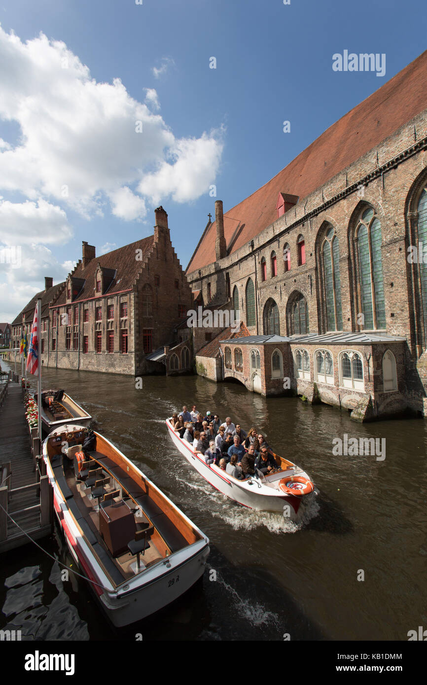 Ville de Bruges, Belgique. les touristes sur un canal en bateau, avec l'hôpital St Jean à droite de l'image. Banque D'Images