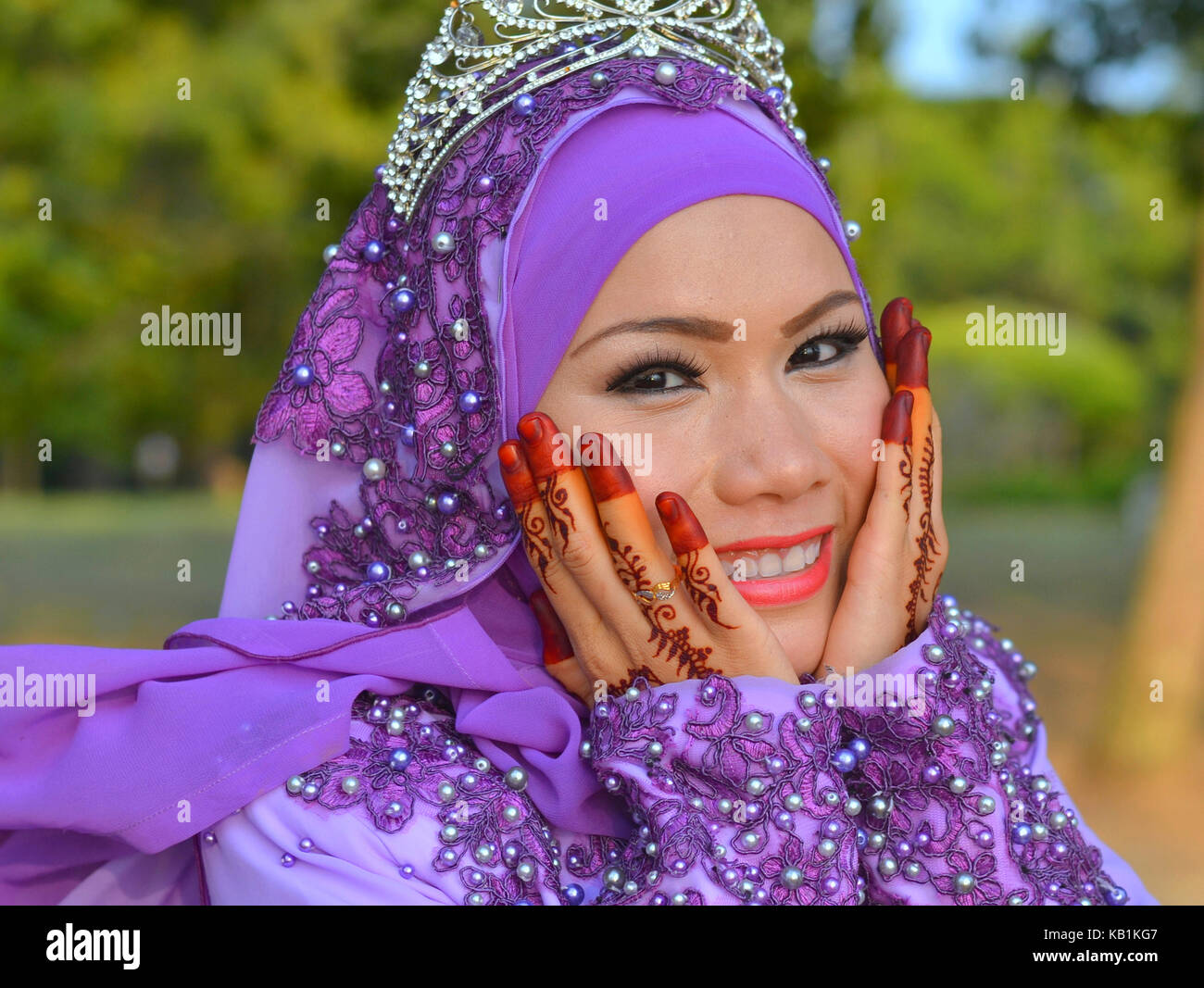 Belle Mariée Malais musulmans traditionnels élaborés avec le maquillage et la suite nuptiale sur les deux mains au henné, portant un hijab mariée bleu et bleu robe de mariage Banque D'Images