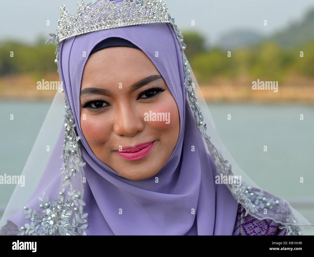 Belle Mariée Malais musulmans traditionnels élaborés avec le maquillage, le port d'un hijab mariée bleu clair avec microphone et de mariée robe de mariage bleu Banque D'Images