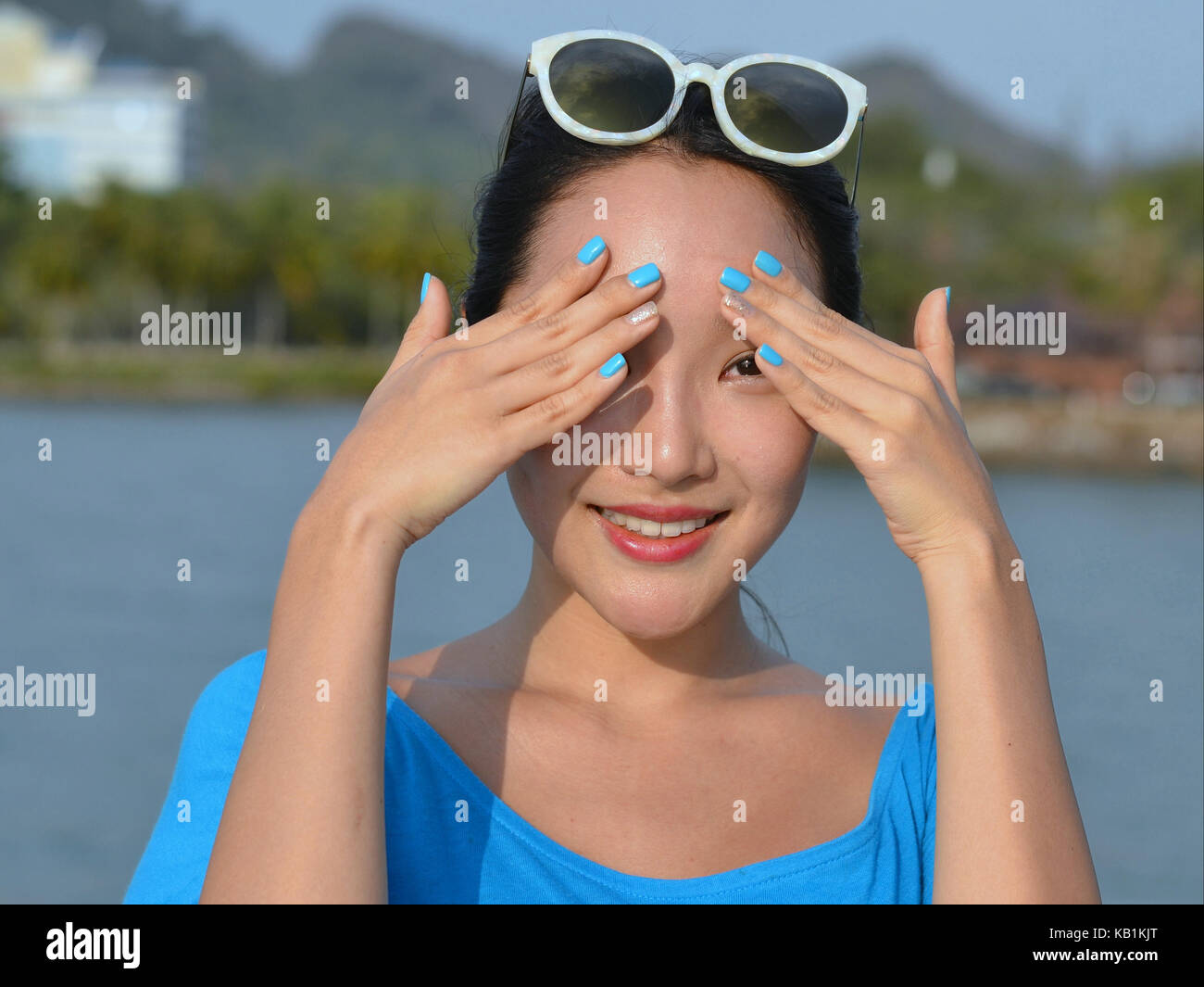 Jeune femme élégante, coréen de Séoul avec les ongles bleus, vêtu de bleu, couvrant ses yeux avec ses mains sensibles contre le soleil aveuglant Banque D'Images