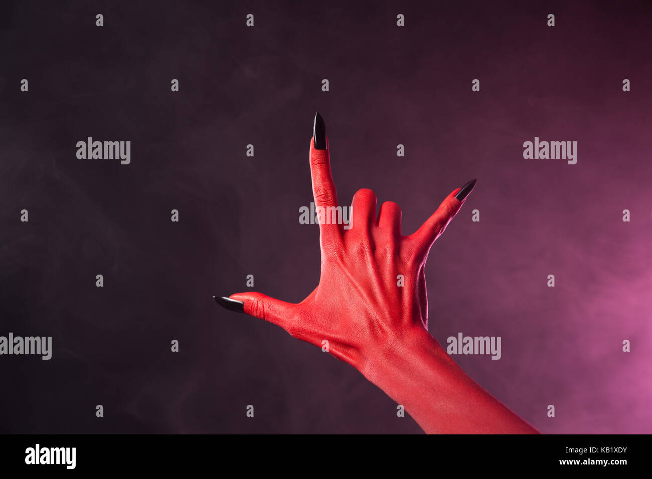 La main du diable rouge noir avec clous montrant heavy metal symbole, thème de l'Halloween Banque D'Images