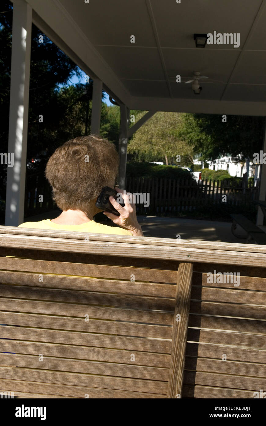 Couple de personnes âgées de race blanche (60 à 70 ans) assis en balancement tout en parlant au téléphone cellulaire. ÉTATS-UNIS Banque D'Images