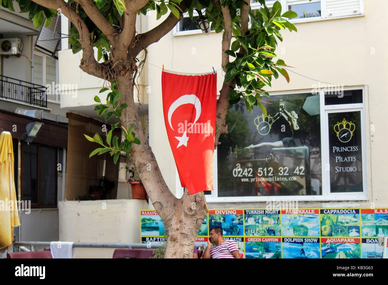 Alanya, Turquie, juillet 2017 : le drapeau turc accroché sur un arbre à droite sur la rue. Banque D'Images