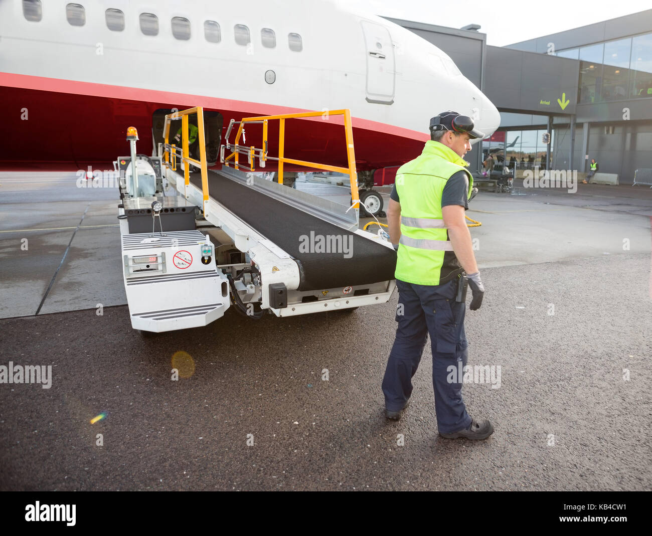 Toute la longueur de l'article travailleurs matures convoyeurs à bagages par avion à joint à la piste de l'aéroport Banque D'Images
