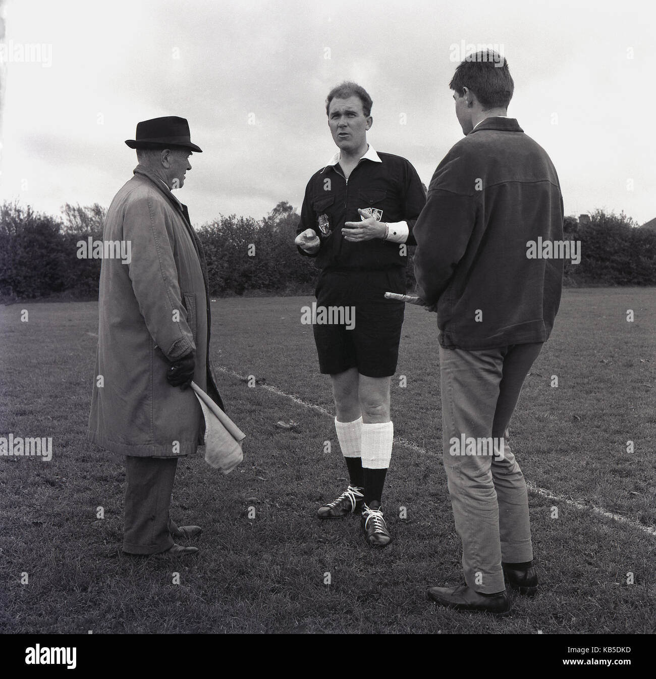 Années 1960, historiques, arbitre de football amateur parle à ses deux juges sur le terrain avant le match, Angleterre, Royaume-Uni. Banque D'Images