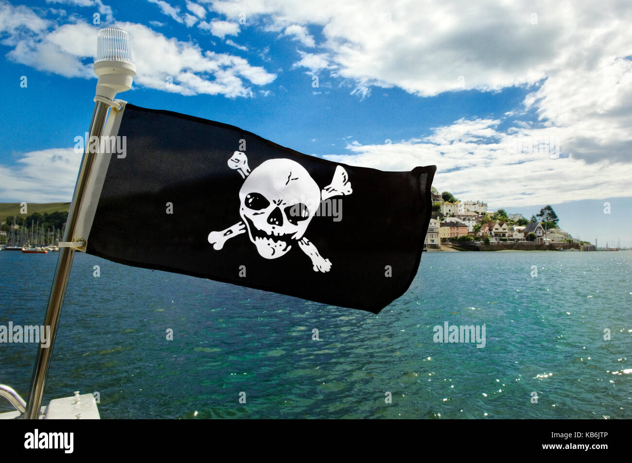 Drapeau Jolly Roger sur un bateau à Dartmouth avec Kingswear, Devon en arrière-plan. Seafood Coast. Pirates Banque D'Images