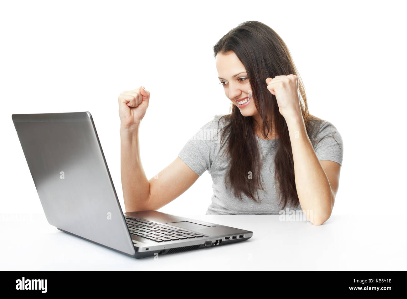 Portrait de jeune femme brune ayant succès en ligne sur son ordinateur portable isolé sur fond blanc Banque D'Images