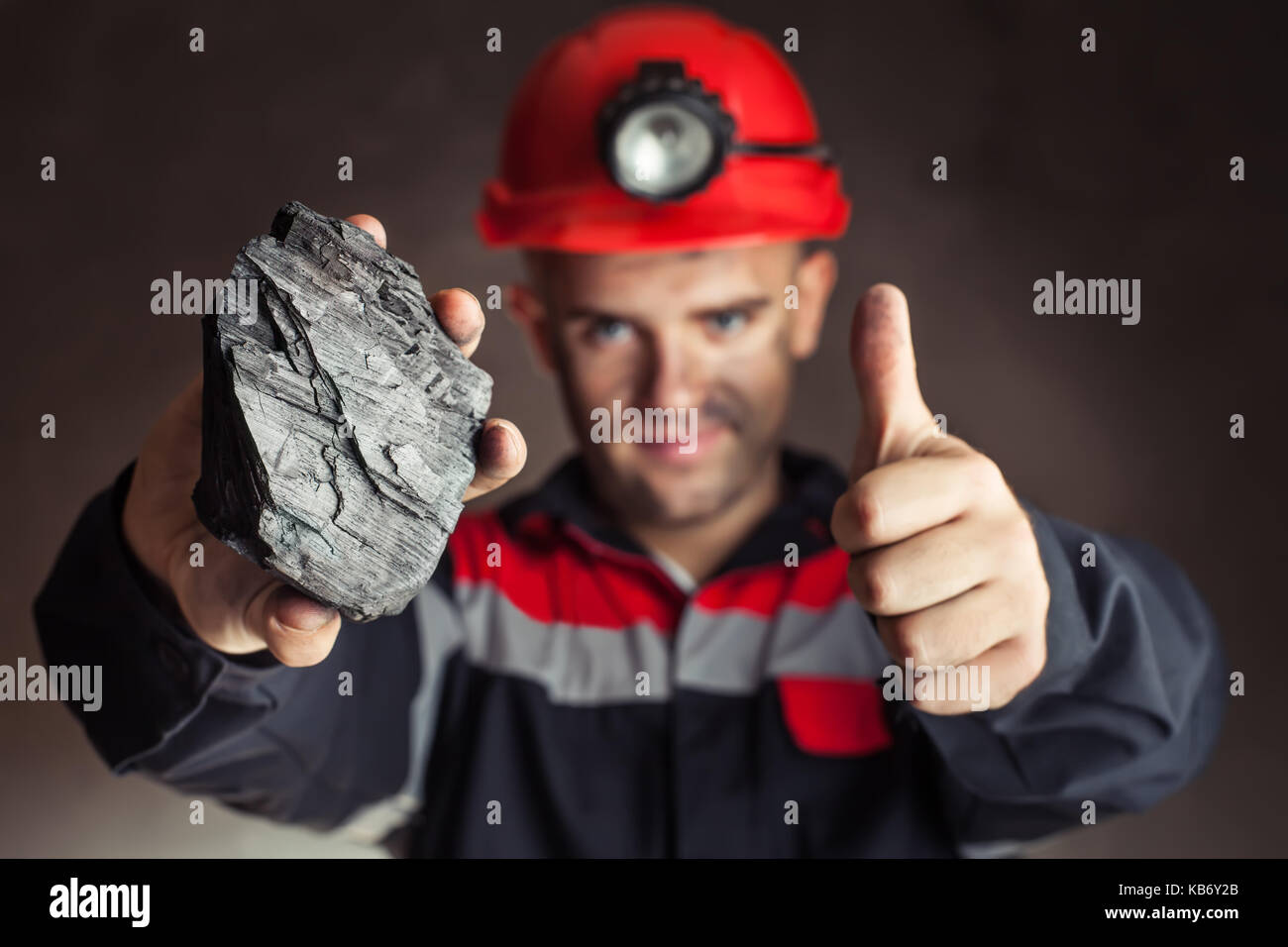 Mineur de charbon montrant bloc de charbon avec Thumbs up sur un fond sombre Banque D'Images