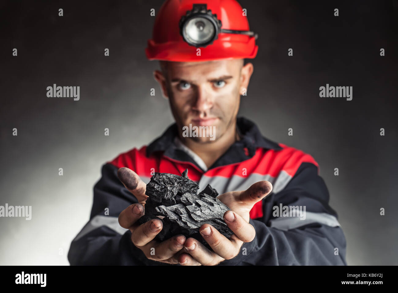 Mineur de charbon holding bloc de charbon contre un fond sombre Banque D'Images