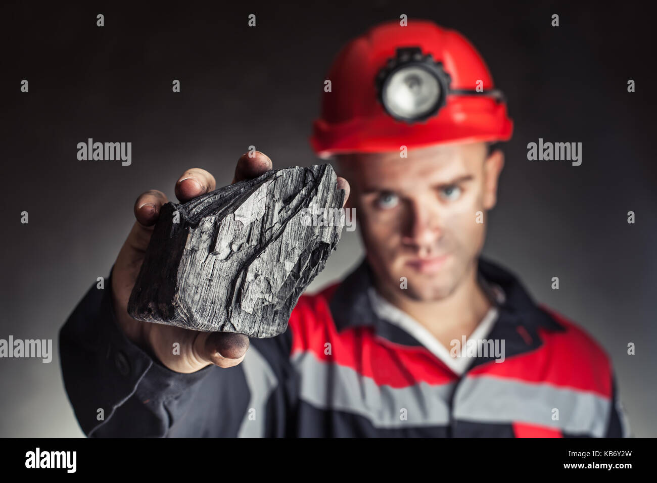 Mineur de charbon montrant bloc de charbon contre un fond sombre Banque D'Images