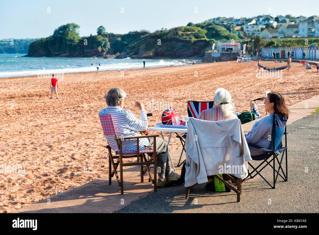 Pique-nique sur la plage de goodrington Sands, à Paignton, dans le sud du Devon. chaises, table du directeur, Union jack, sables rouges et la mer soleil d'été. Banque D'Images