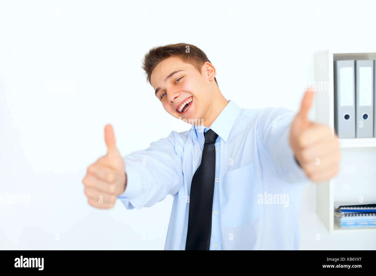 Portrait of young laughing woman showing Thumbs up in office Banque D'Images