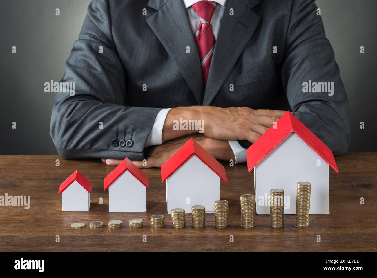 Portrait of businessman avec différentes tailles de maisons et des piles de jetons sur le tableau Banque D'Images