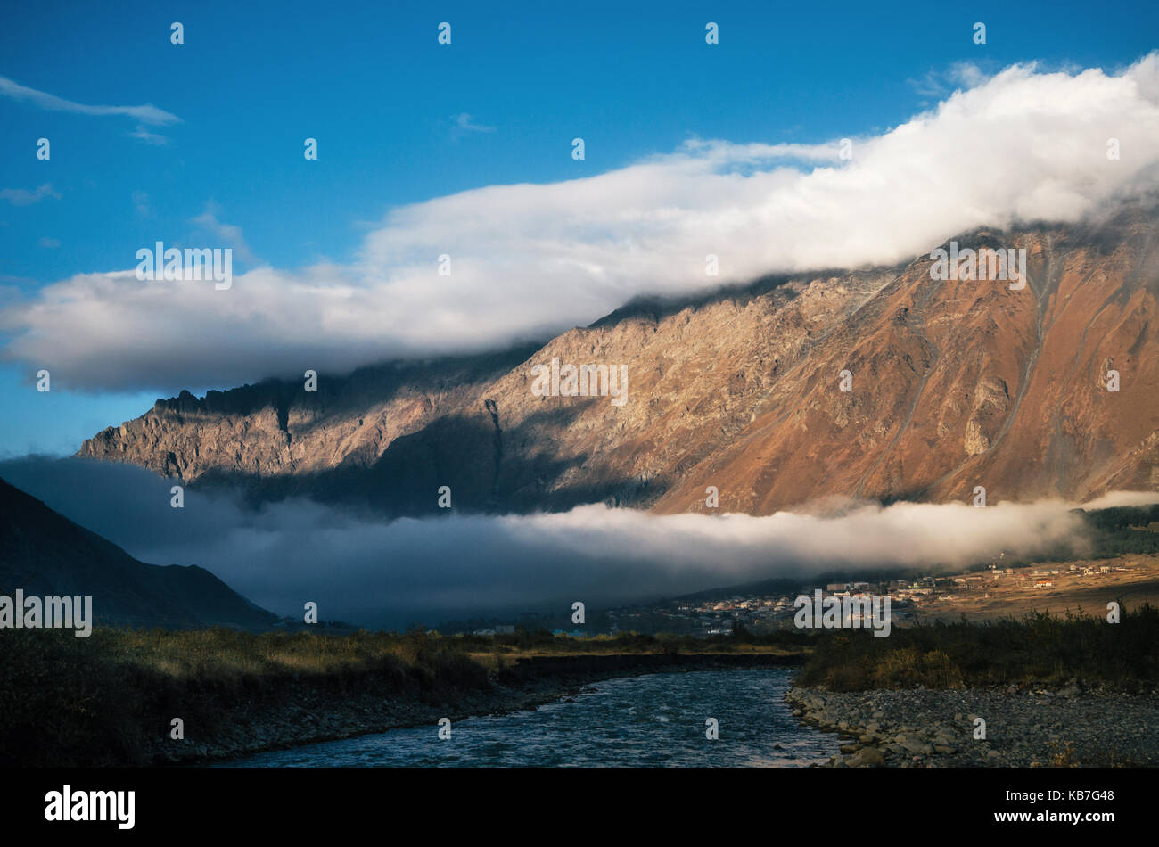 Double différentes couches de nuages sur stepantsminda kazbegi village et pic de brown mountain, Géorgie. scenic paysage d'automne. Banque D'Images