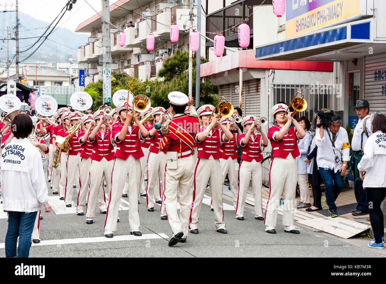 Défilé annuel de Genji, Tada, au Japon. Women's Wind Band, vêtu d'une tunique rose et un pantalon blanc, debout dans la rue. Face à la vue. Banque D'Images