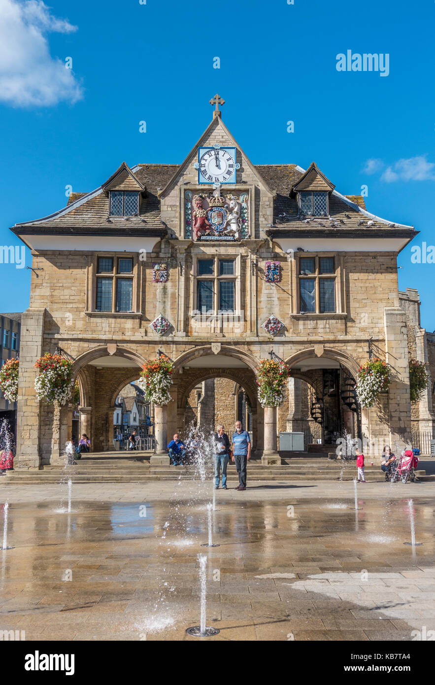 Les gens autour de l'historique du 17ème siècle, baignée de Guildhall (également connu sous le nom de Croix de beurre), dans le centre-ville de Peterborough, Cambridgeshire, Angleterre, Royaume-Uni. Banque D'Images