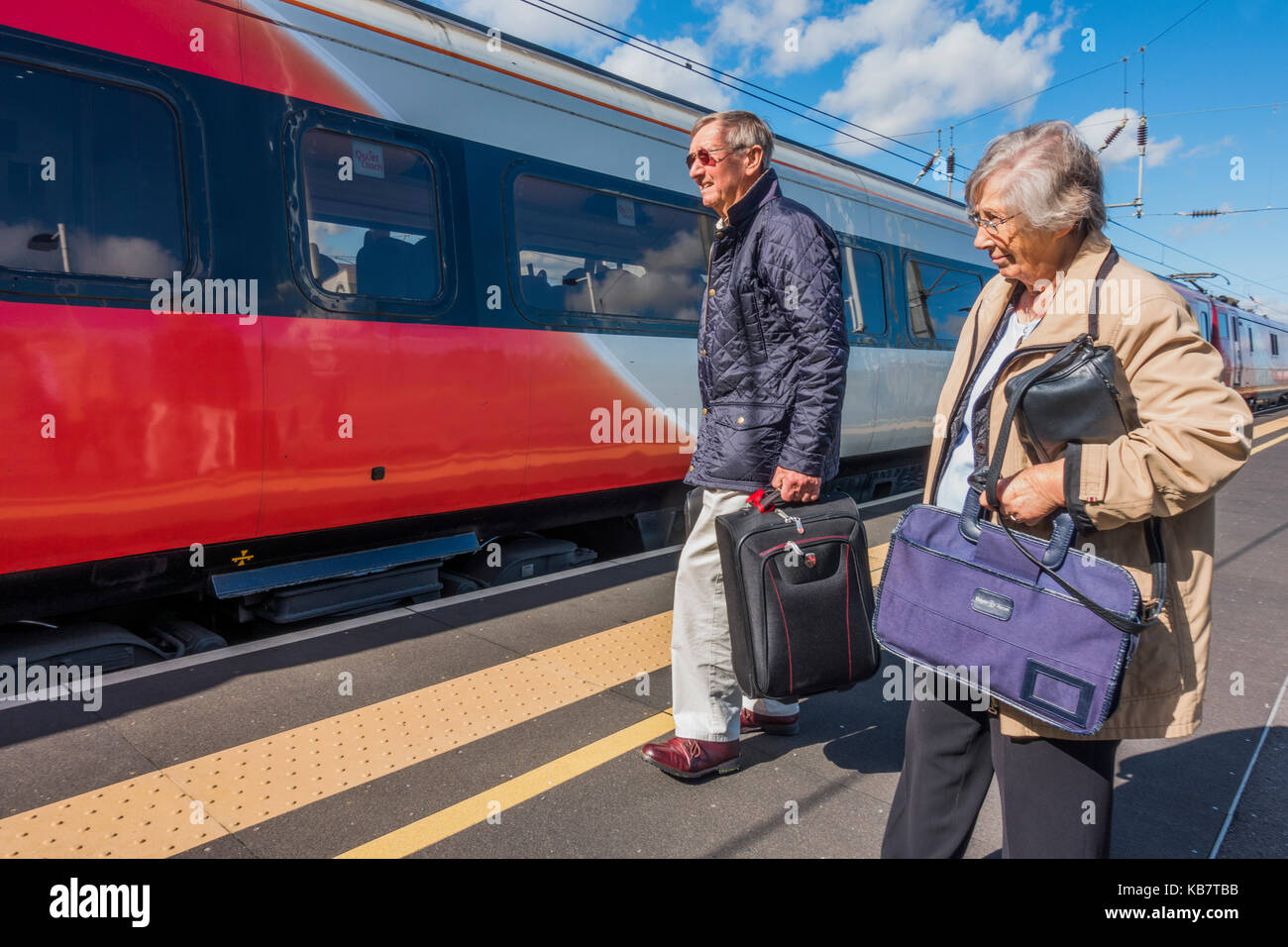 Un couple de personnes âgées debout sur une plate-forme, sur le point de sélection une vierge jusqu'à la gare de Kings Cross à Peterborough, gare, Cambridgeshire, Angleterre, Royaume-Uni. Banque D'Images