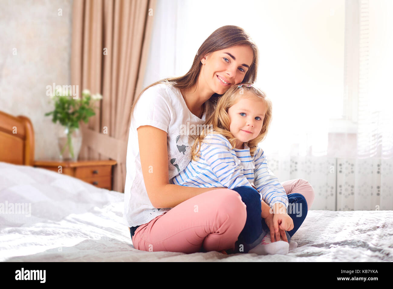 Portrait de Mère et fille sur le lit par la fenêtre. Banque D'Images