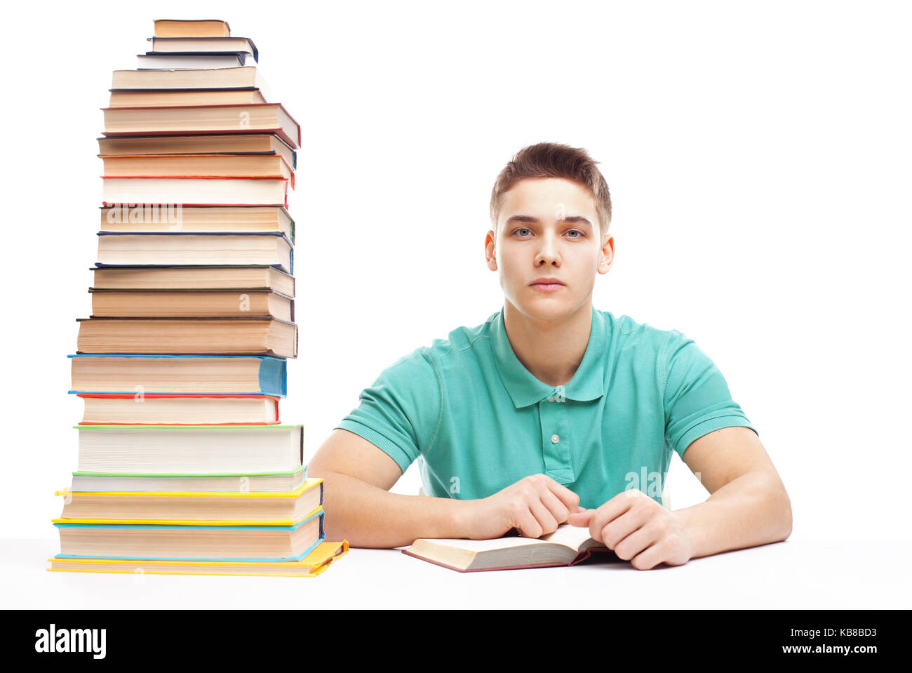 Étudiant étranger à une table avec une haute pile de livres isolé sur fond blanc Banque D'Images