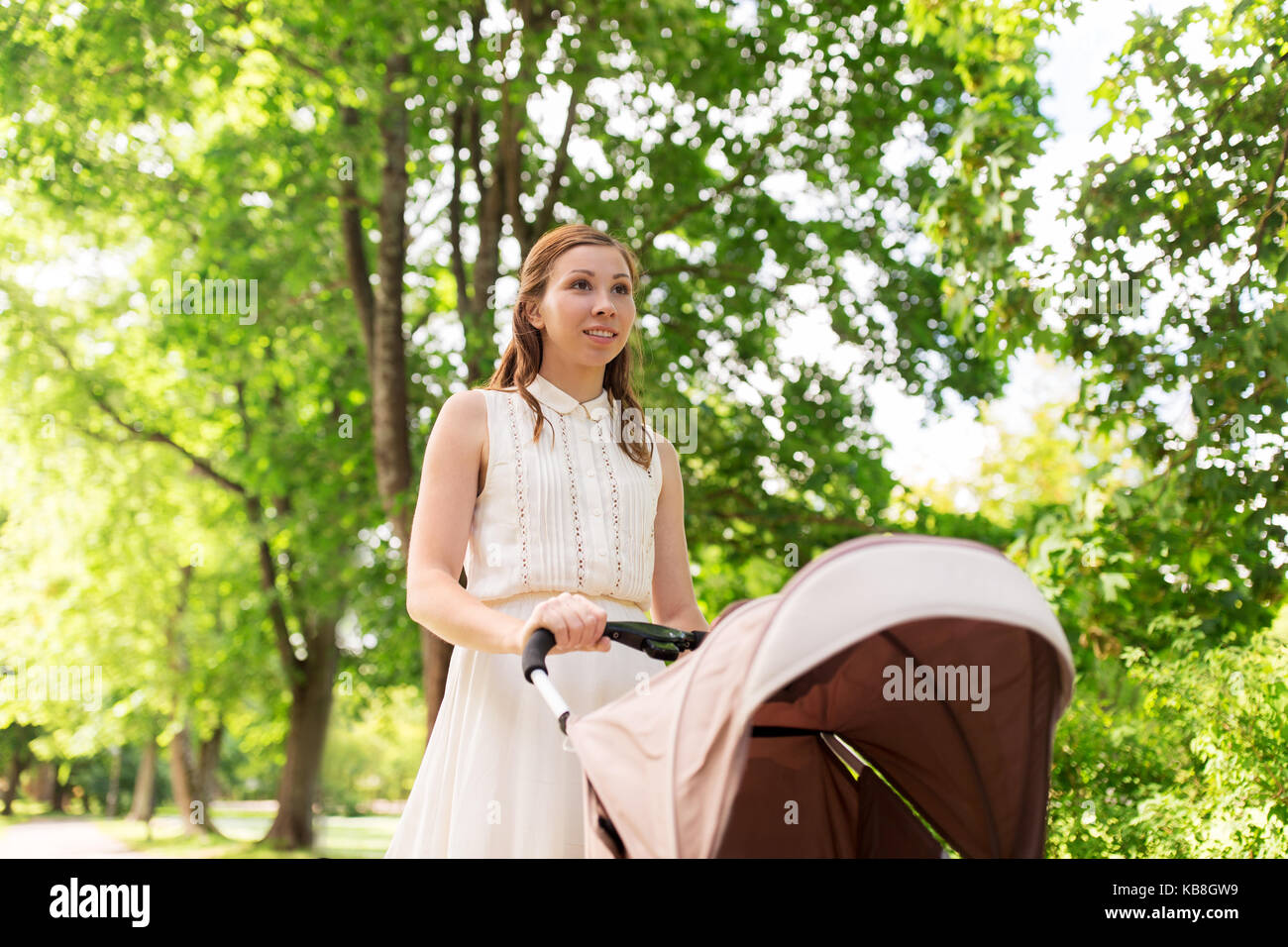 Heureuse Mère avec enfant en poussette au parc d'été Banque D'Images