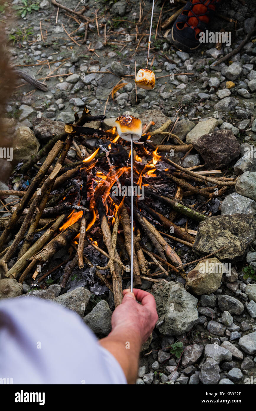 Point de vue tourné d'une woman toasting une guimauve au-dessus d'un feu ouvert. UK Banque D'Images