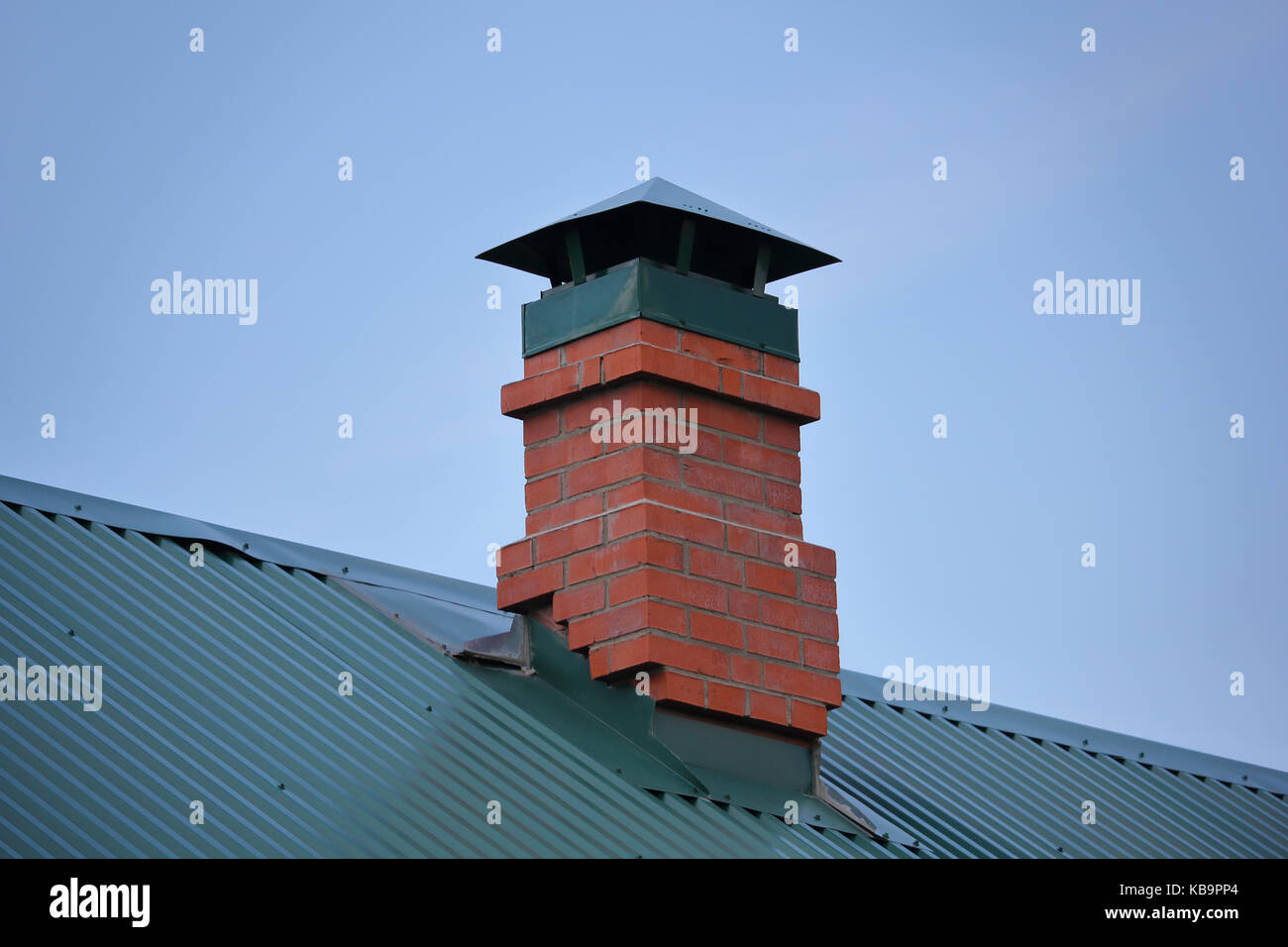 Cheminée en brique sur le toit métallique vert photo Banque D'Images