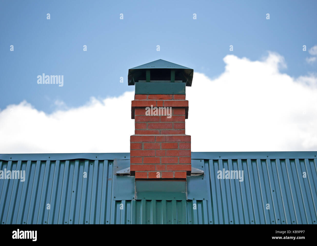 Cheminée en brique sur le toit métallique vert photo Banque D'Images