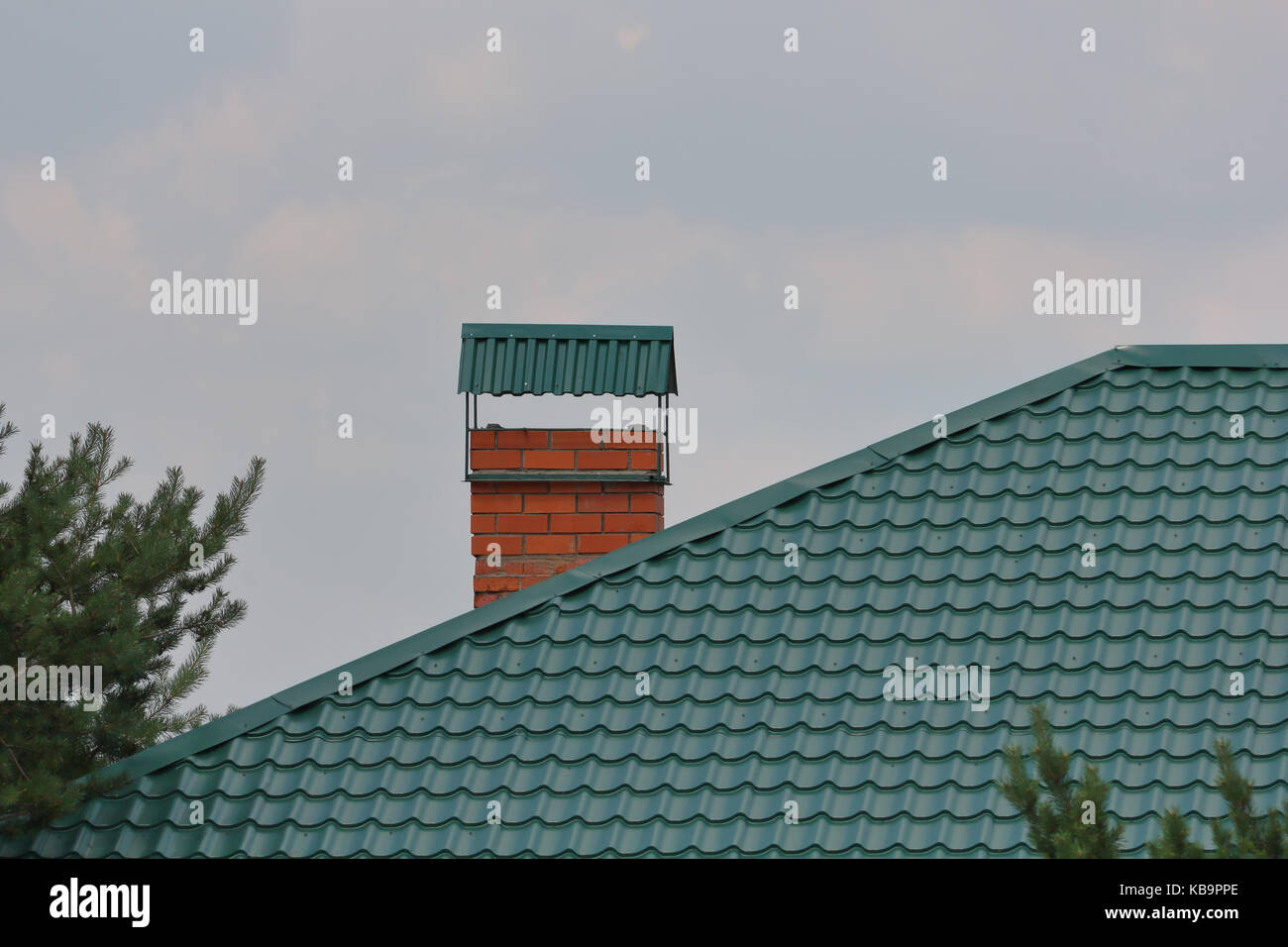 Cheminée en brique sur le toit métallique vert photo Banque D'Images