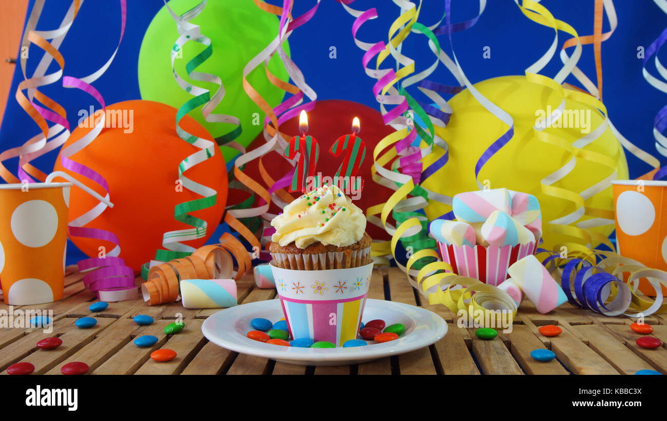 22 birthday cupcake avec bougies sur table en bois rustique avec fond de ballons colorés verres en plastique bonbons sur mur bleu en arrière-plan Banque D'Images