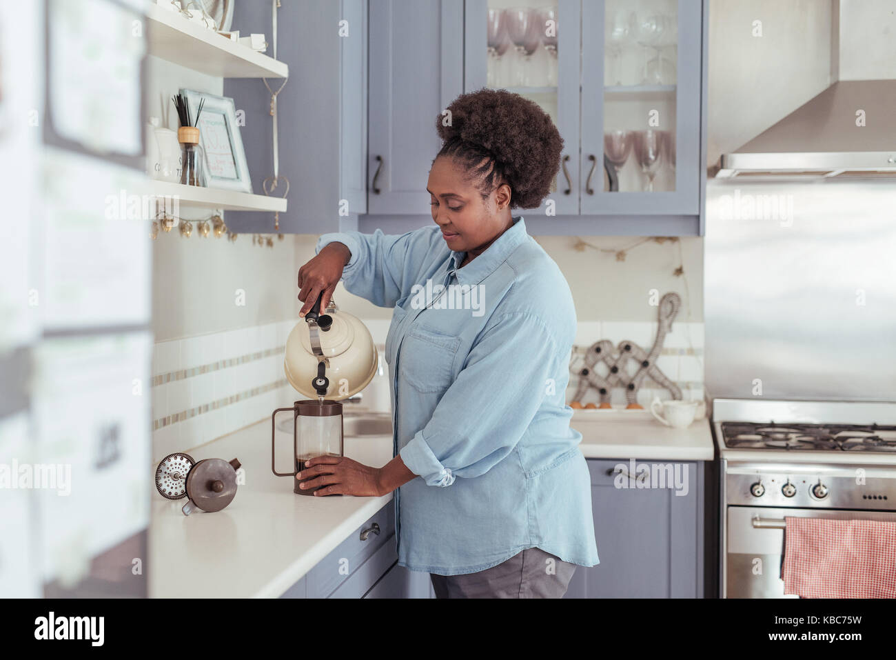 Jeune femme africaine la préparation du café frais dans sa cuisine Banque D'Images