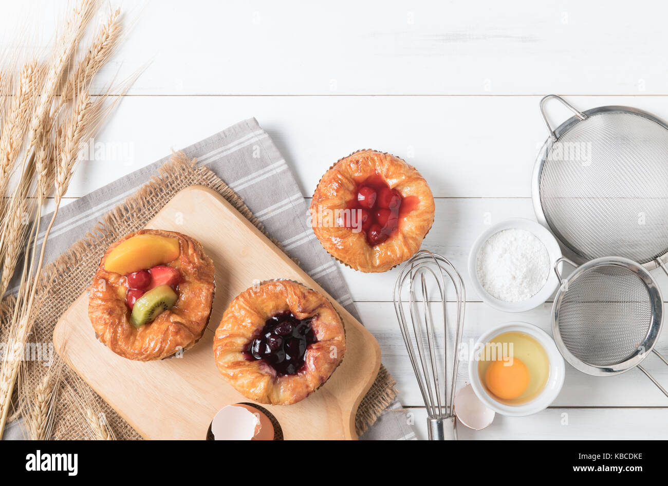 Pain danois avec des fruits, de bleuet et de la sauce aux cerises et à l'équipement sur fond de bois blanc, de l'alimentation boulangerie Banque D'Images