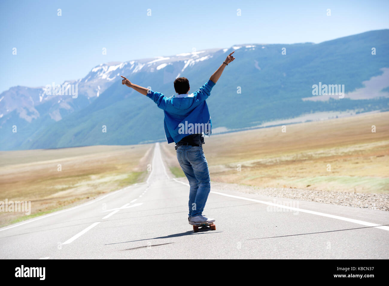 Man skating longboard tout droit la route des montagnes Banque D'Images