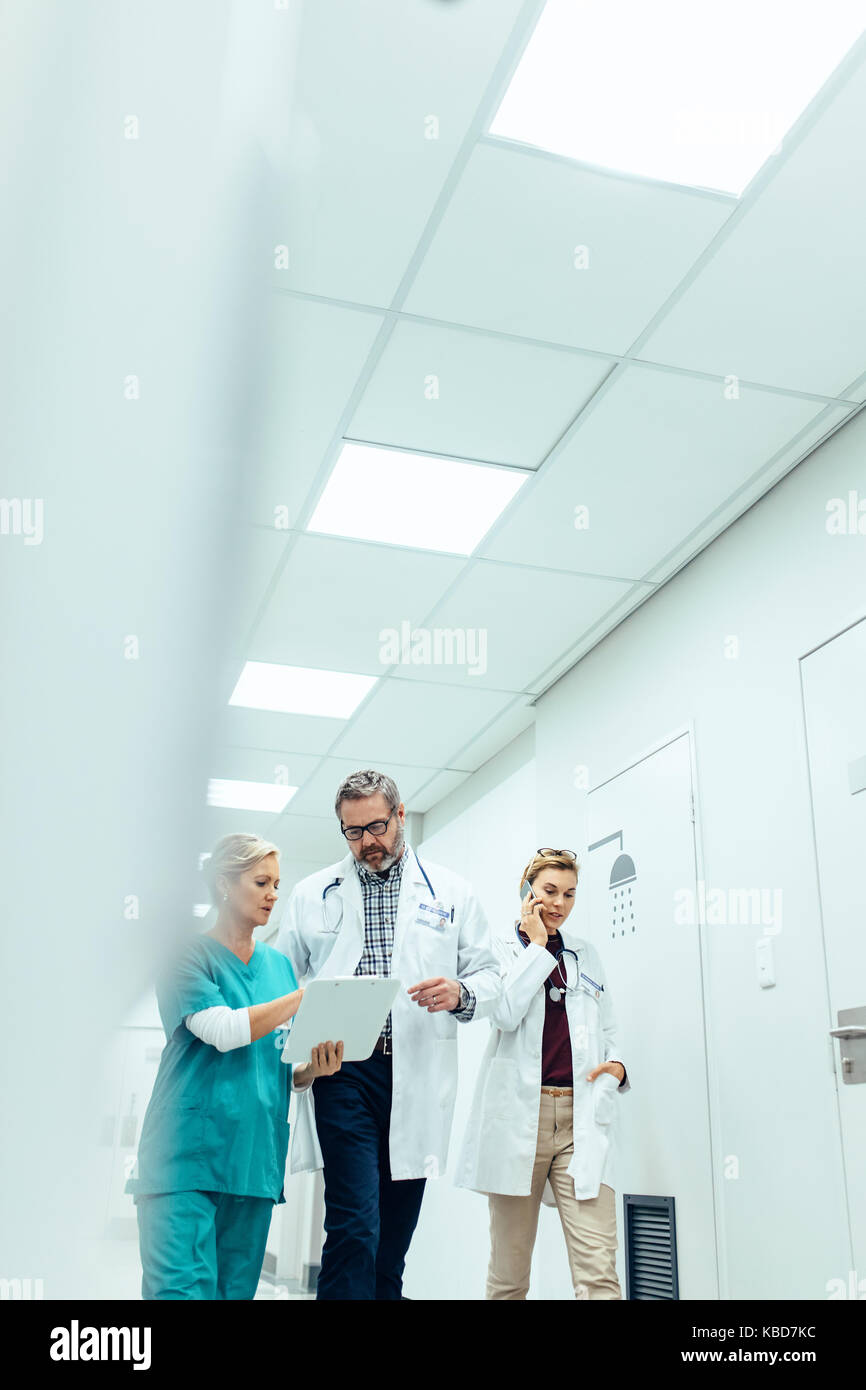 L'équipe médicale marchant dans le couloir de l'hôpital. Groupe de médecins walking in hospital corridor et de discussions. Banque D'Images