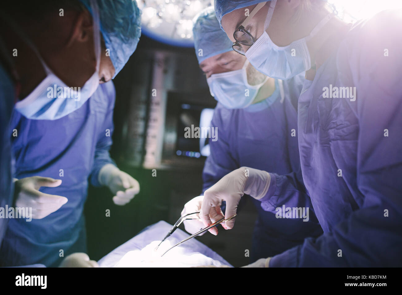 Chirurgienne avec son équipe d'effectuer une chirurgie le patient en salle d'opération de l'hôpital. Les médecins au cours de l'intervention en salle d'opération. Banque D'Images