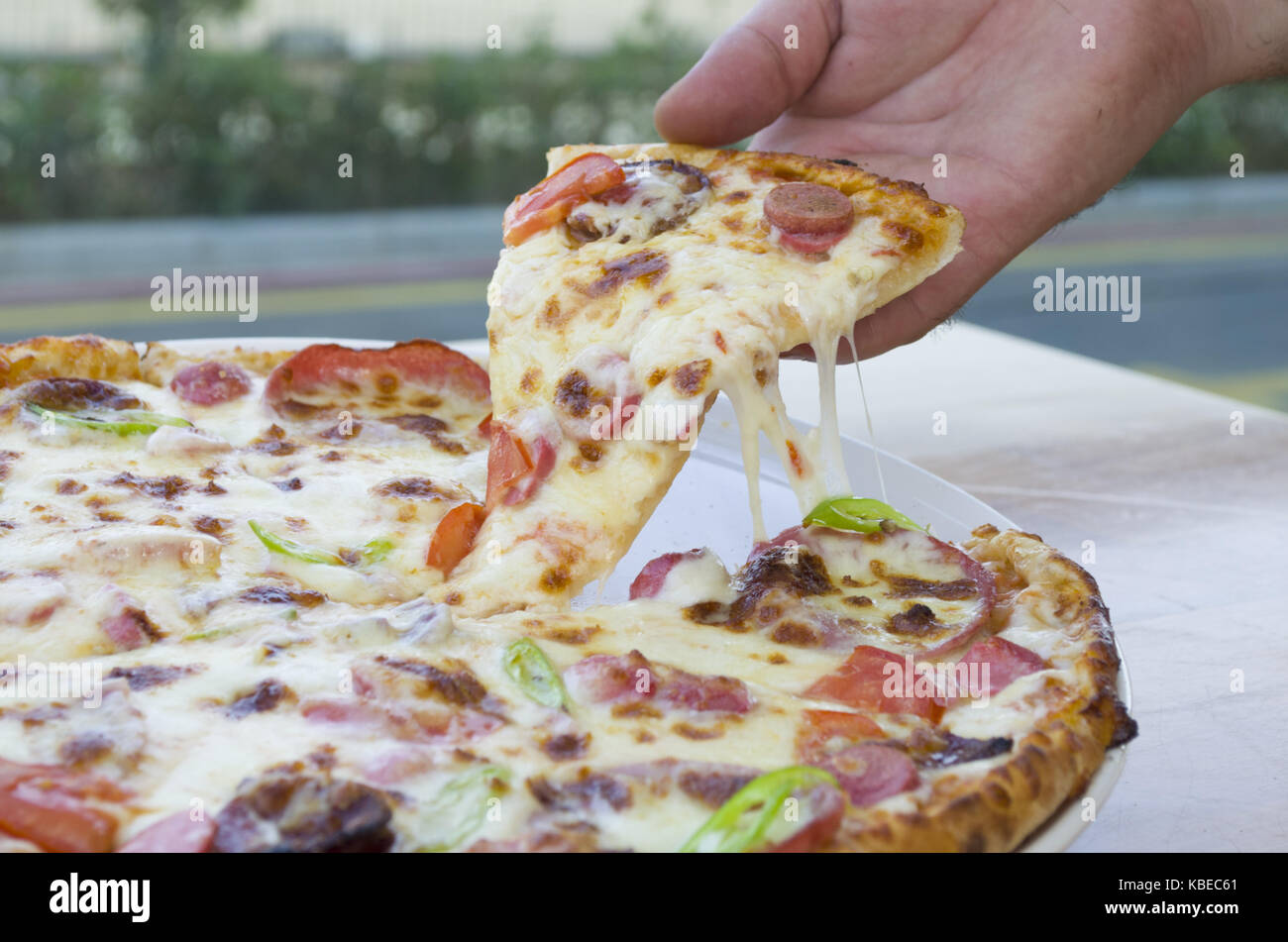 Une tranche de pizza à la main un beau fonds de restaurant Banque D'Images