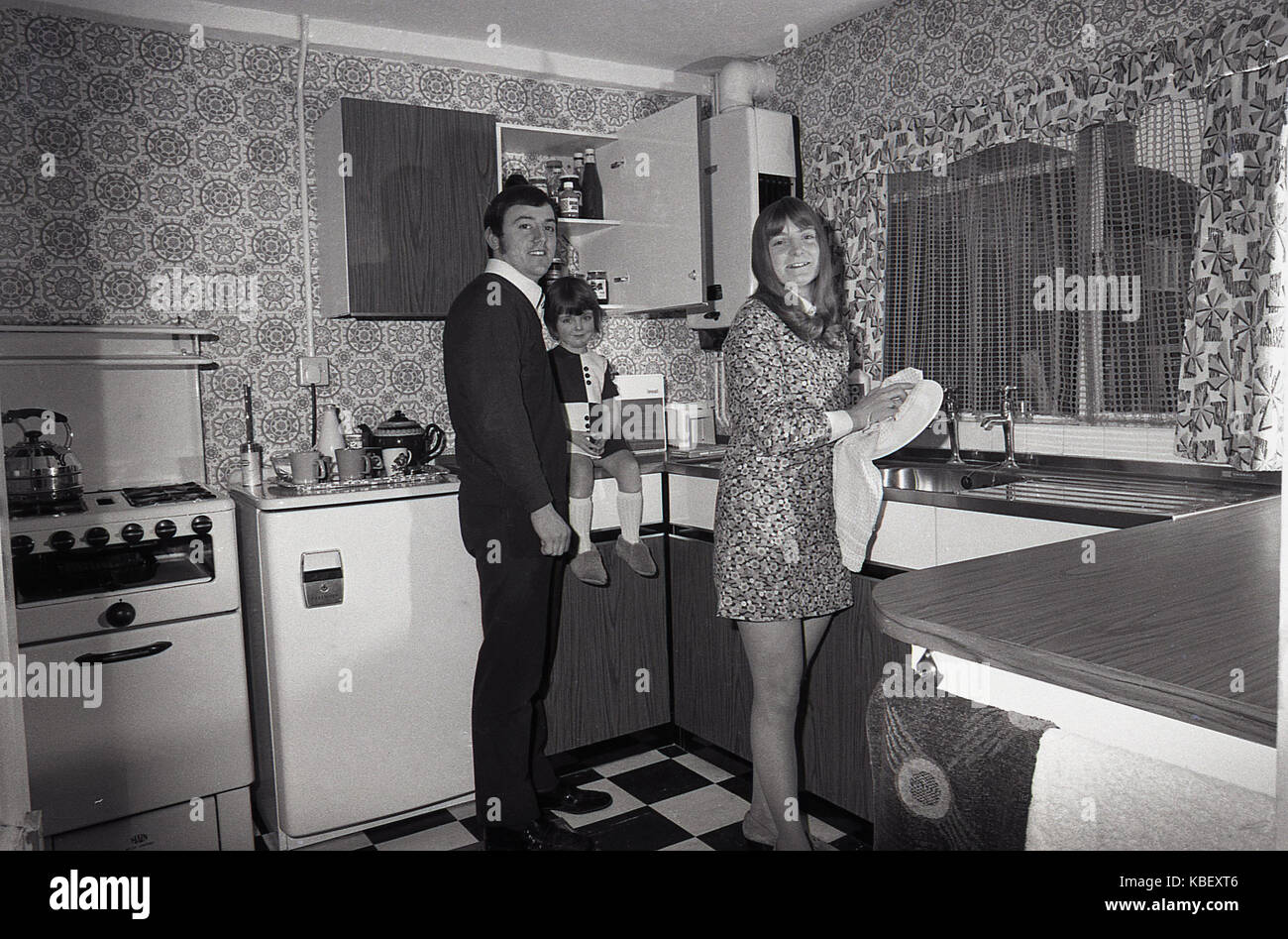 1972, historiques, mari et femme avec enfant dans la cuisine de leur conseil, récemment rénové, appartement rue de Baildon, Deptford, London, SE8, Angleterre, Royaume-Uni. Banque D'Images