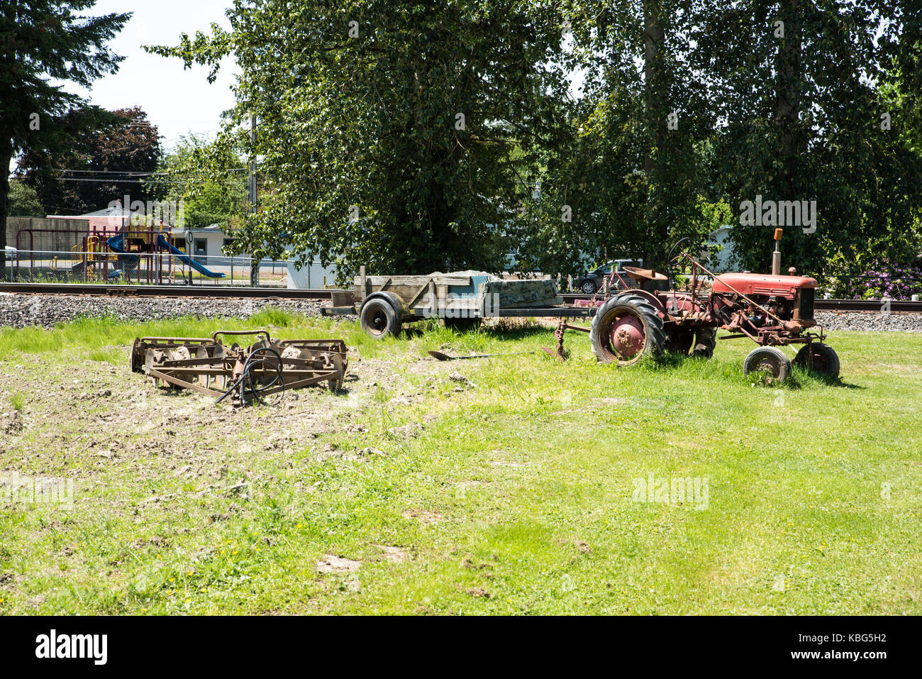 La voie du tracteur et remorque-a utilisé le tracteur avec une remorque est assis dans un champ à côté d'une voie de chemin de fer. Banque D'Images
