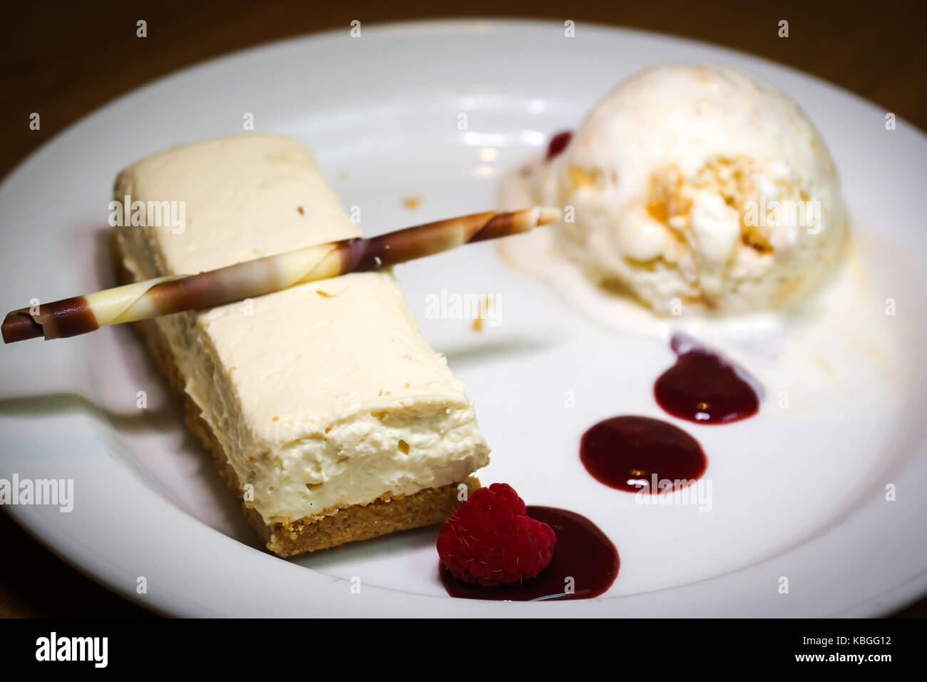 Un gâteau au fromage au chocolat blanc couplé avec une crème glacée vanille miel et un coulis de framboise Banque D'Images