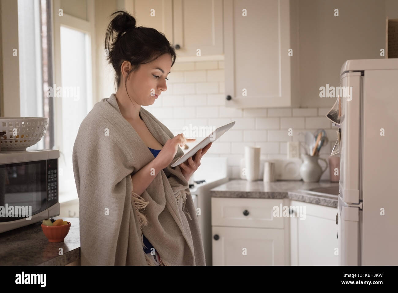 Young woman using tablet computer en étant debout dans la cuisine à la maison Banque D'Images
